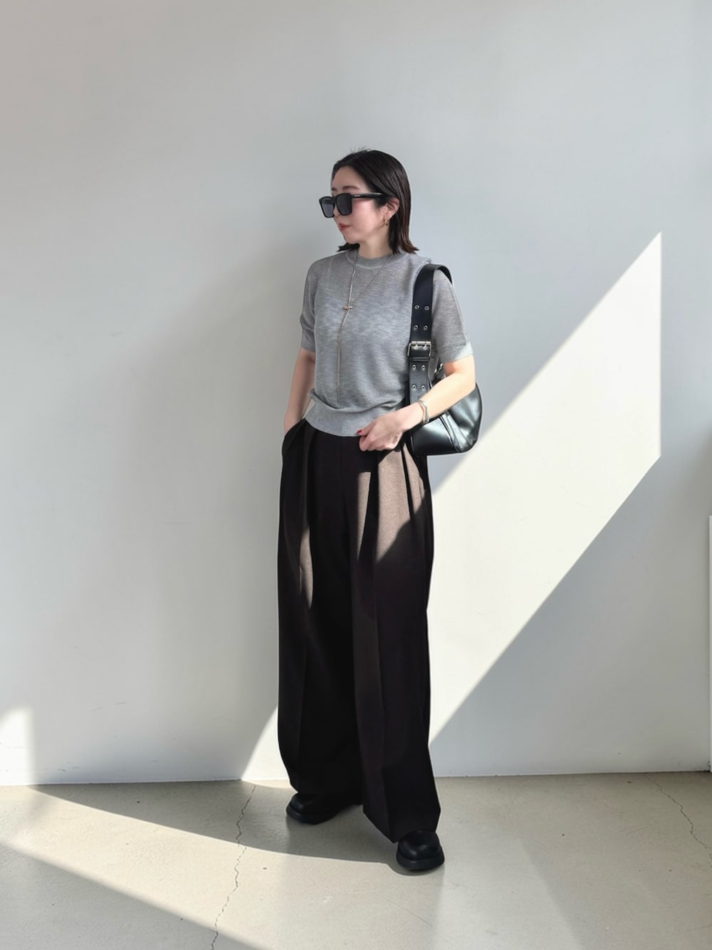 グレー系のニット/セーター、ブラウン系のその他パンツ、ブラック系のその他シューズを着用したレディースの春コーディネートの1枚目の写真