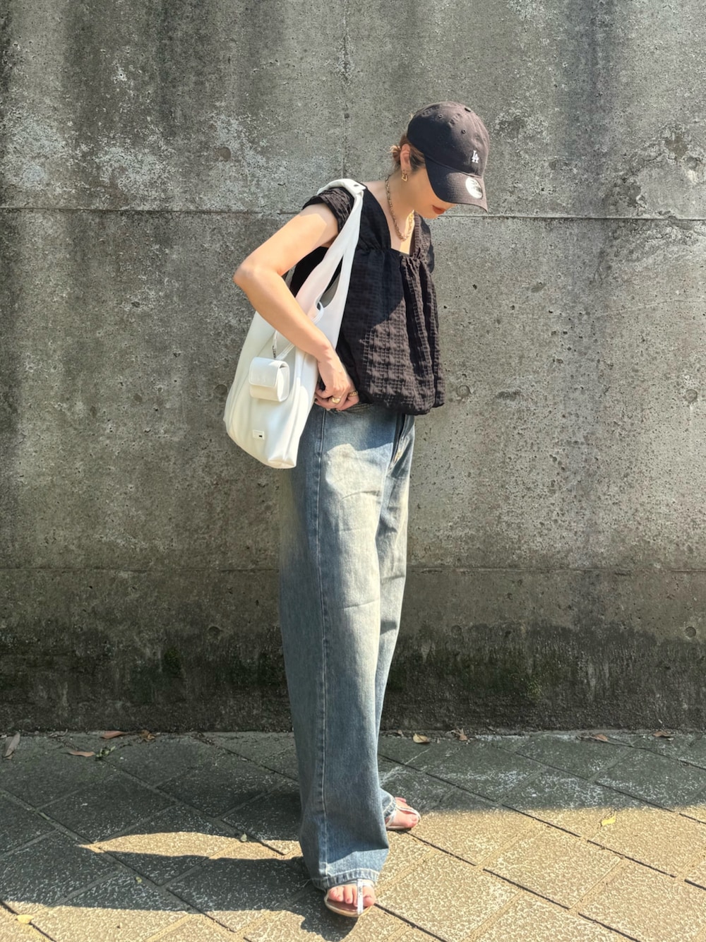ホワイト系のトートバッグ、ブルー系のデニムパンツ、シルバー系のサンダルを着用したレディースの夏コーディネートの1枚目の写真