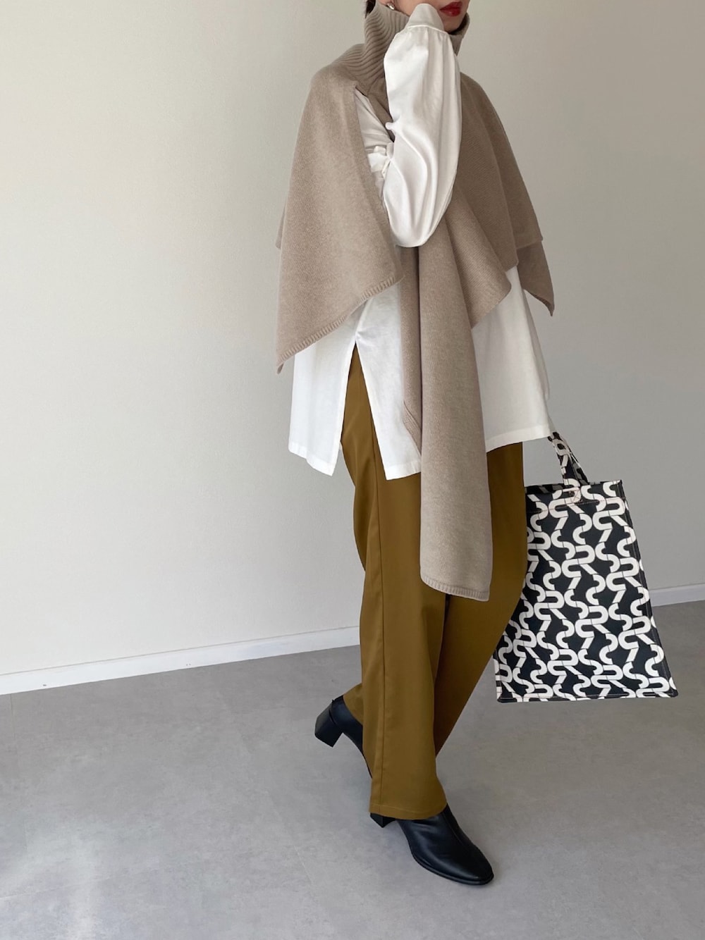 ベージュ系のベスト、イエロー系のその他パンツ、ブラック系のブーツを着用したレディースの冬コーディネートの1枚目の写真