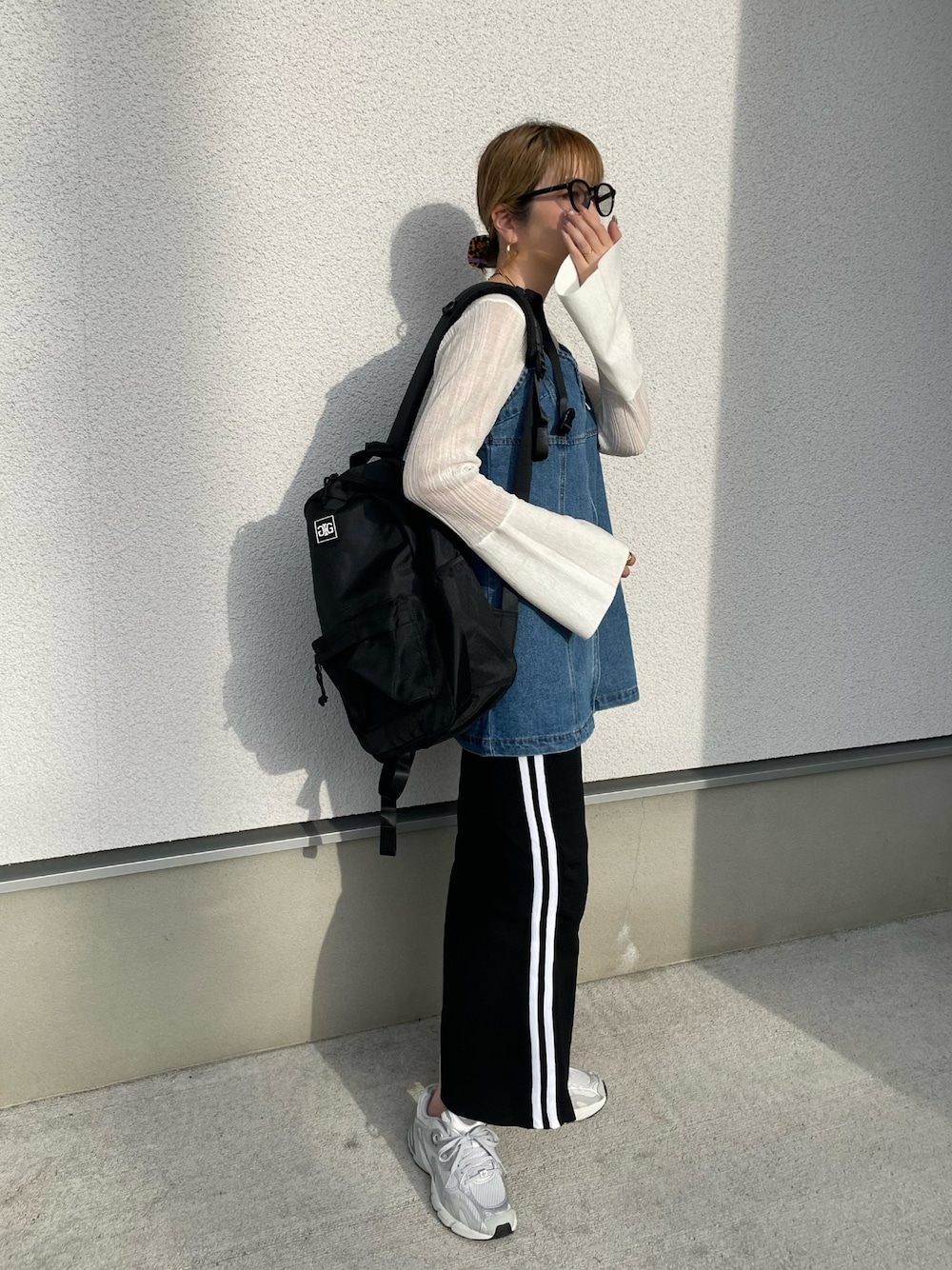 ブラック系のバックパック/リュック、ホワイト系のニット/セーター、グレー系のスニーカーを着用したレディースの秋コーディネートの1枚目の写真