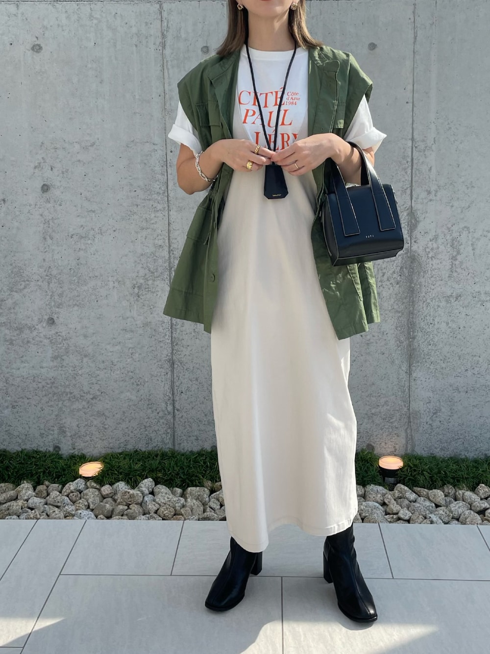 ブラック系のブーツ、ベージュ系のジャンパースカート、ブラック系のボストンバッグを着用したレディースの秋コーディネートの1枚目の写真