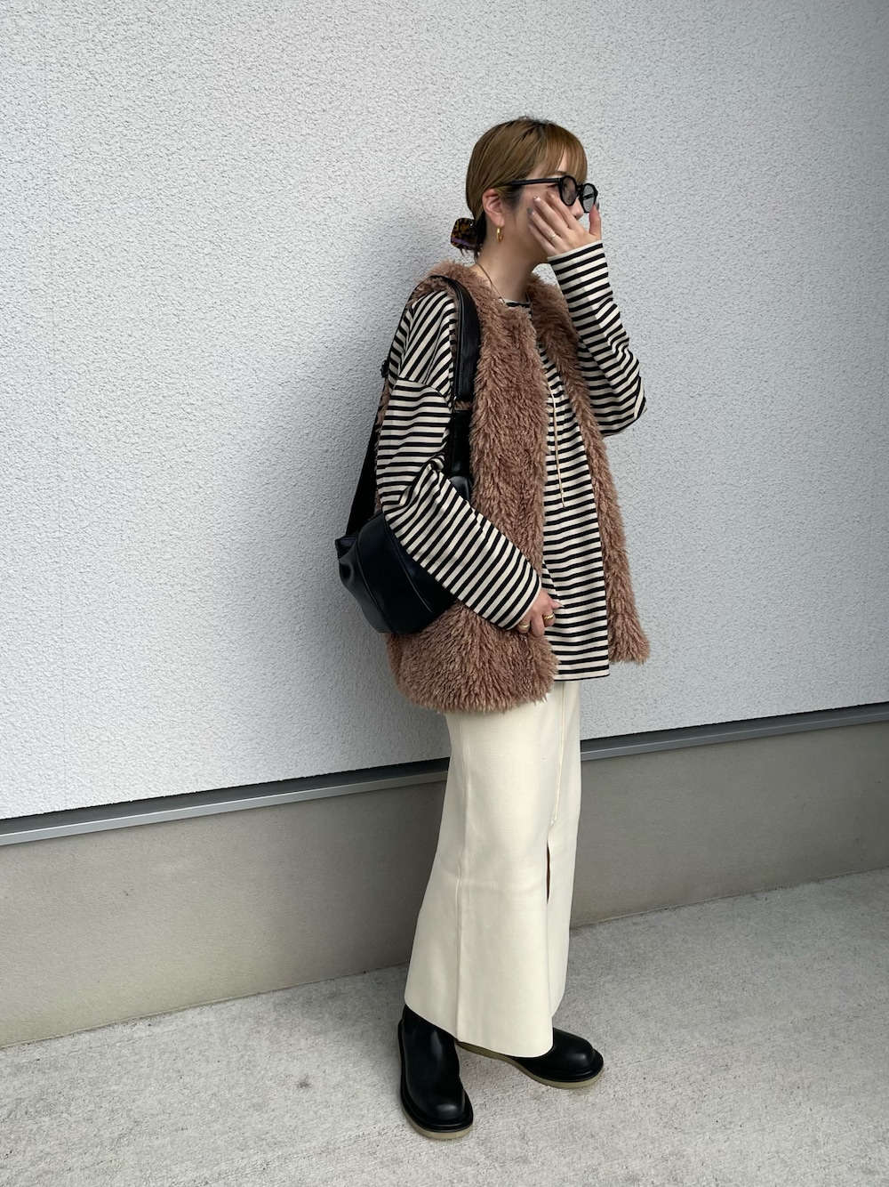 ホワイト系のスカート、ベージュ系のTシャツ/カットソー、ブラック系のブーツを着用したレディースの秋コーディネートの1枚目の写真