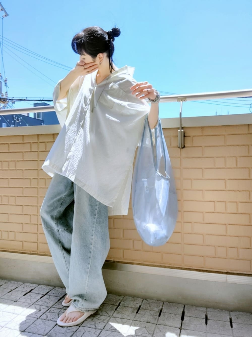 ホワイト系のサンダル、ブルー系のデニムパンツ、ブルー系のトートバッグを着用したレディースの夏コーディネートの1枚目の写真