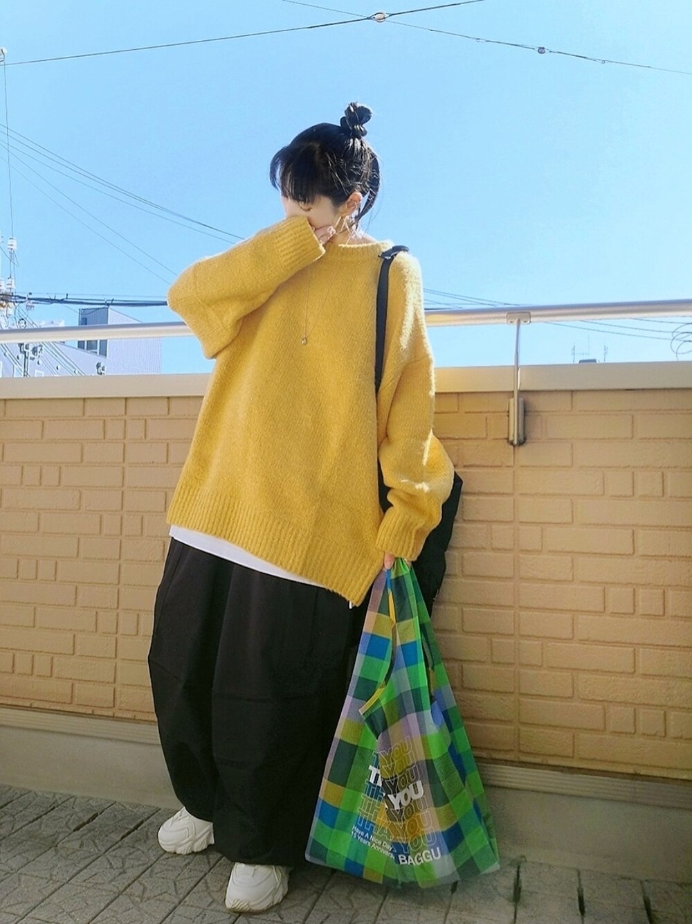 イエロー系のニット/セーター、ブラック系のバックパック/リュック、グリーン系のショルダーバッグを着用したレディースの秋コーディネートの1枚目の写真