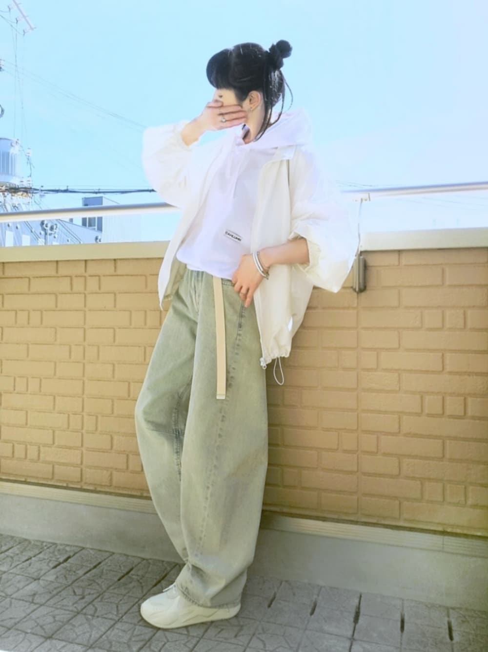 ホワイト系のスニーカー、ブルー系のデニムパンツ、ホワイト系のナイロンジャケットを着用したレディースの春コーディネートの1枚目の写真