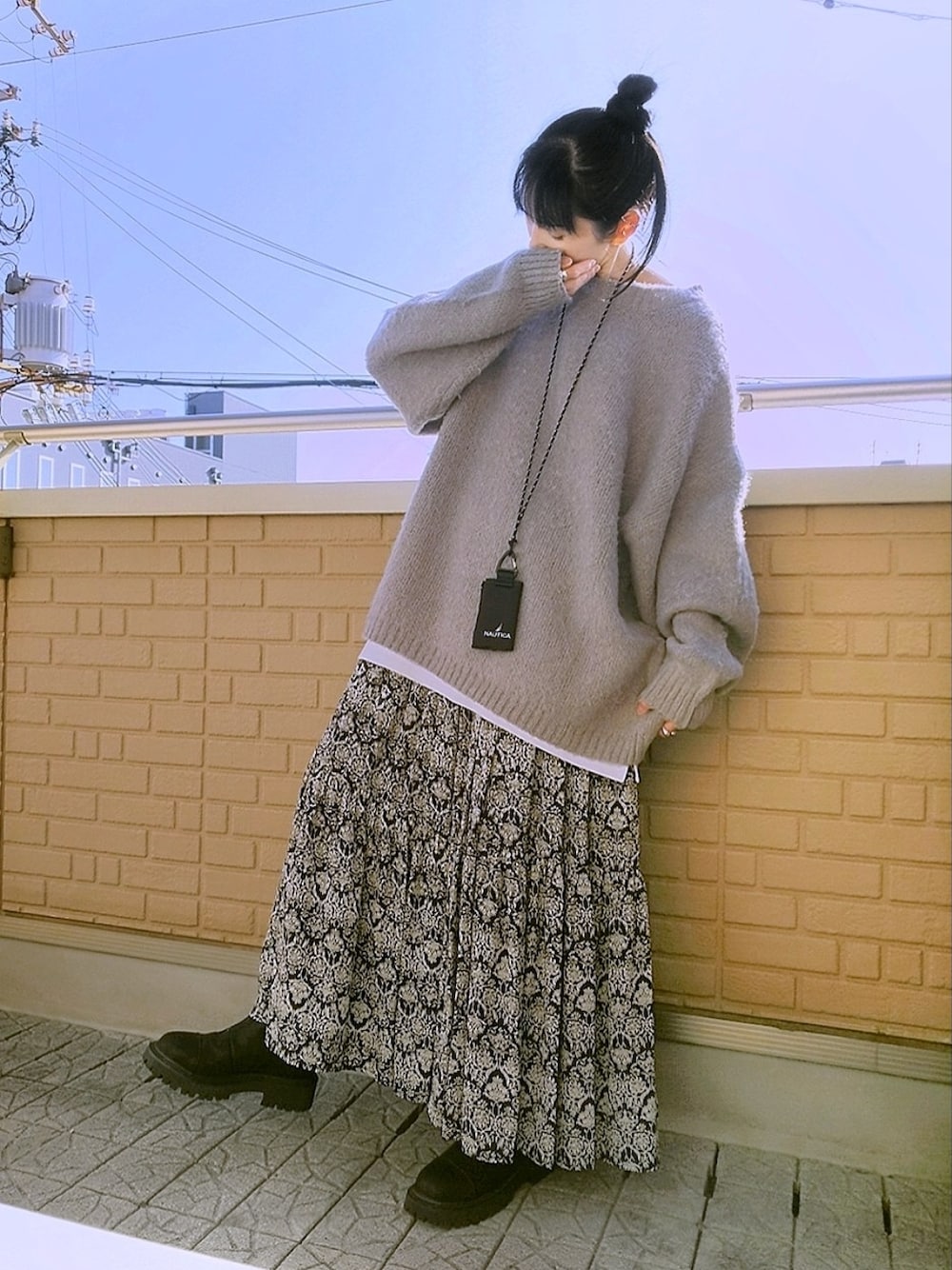 グレー系のニット/セーター、ブラック系のスカート、ブラック系のブーツを着用したレディースの冬コーディネートの1枚目の写真
