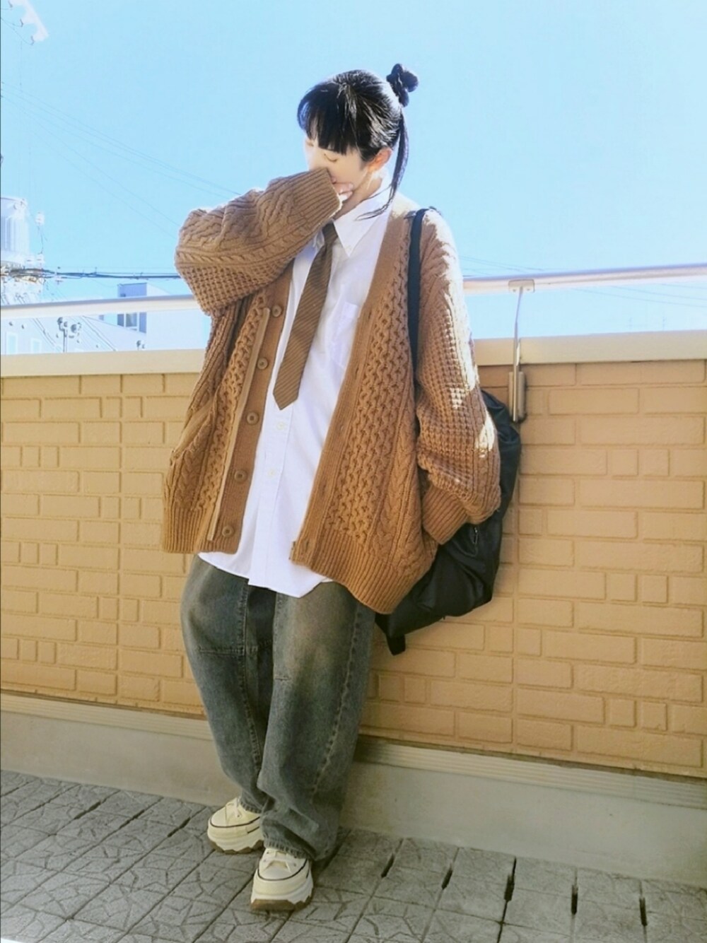 ホワイト系のスニーカー、ブルー系のデニムパンツ、ベージュ系のニット/セーターを着用したレディースの秋コーディネートの1枚目の写真