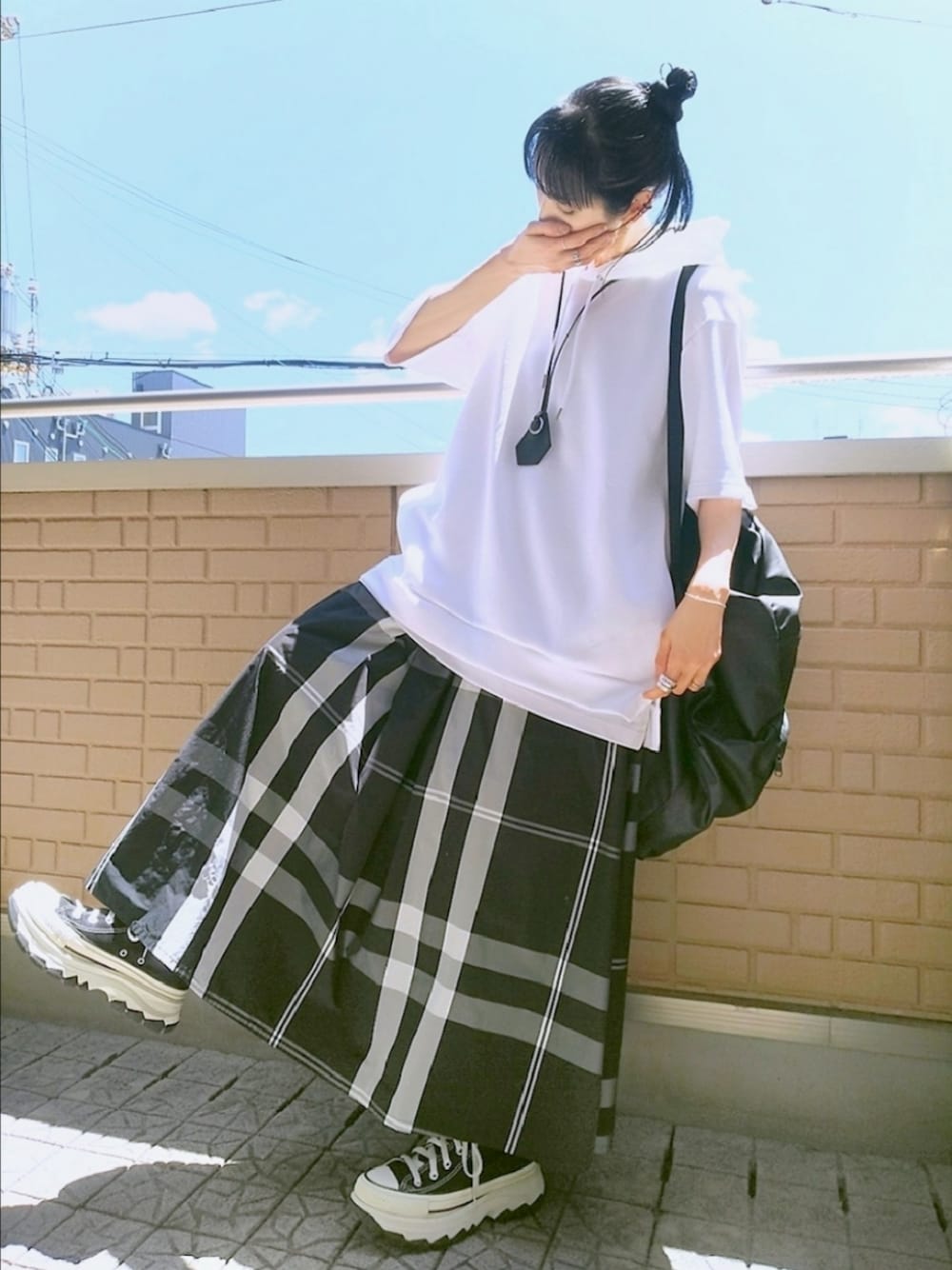 ブラック系のスニーカー、ブラック系のスカート、ホワイト系のパーカーを着用したレディースの春コーディネートの1枚目の写真