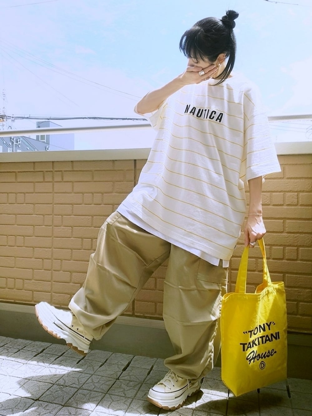イエロー系のトートバッグ、ホワイト系のスニーカー、ベージュ系のカーゴパンツを着用したレディースの夏コーディネートの1枚目の写真