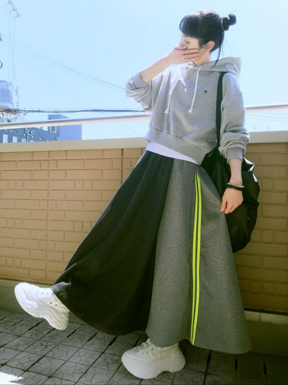 ホワイト系のスニーカー、ブラック系のスカート、グレー系のパーカーを着用したレディースの春コーディネートの1枚目の写真