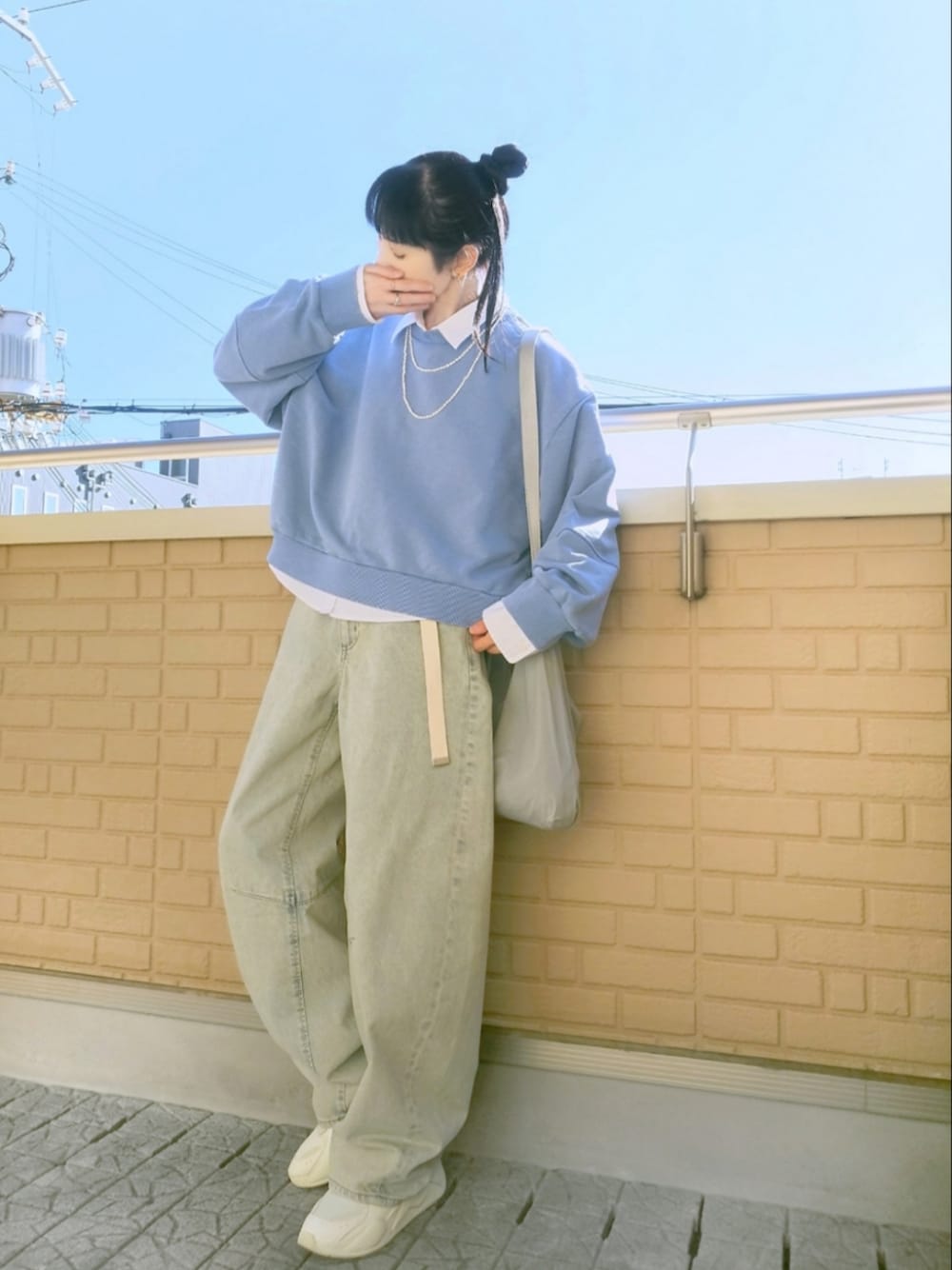 ホワイト系のスニーカー、ブルー系のデニムパンツ、グレー系のショルダーバッグを着用したレディースの冬コーディネートの1枚目の写真