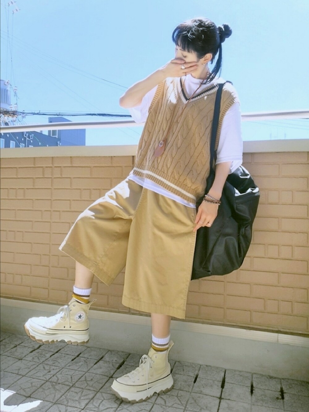 ホワイト系のスニーカー、ベージュ系のチノパンツ、ベージュ系のベストを着用したレディースの秋コーディネートの1枚目の写真