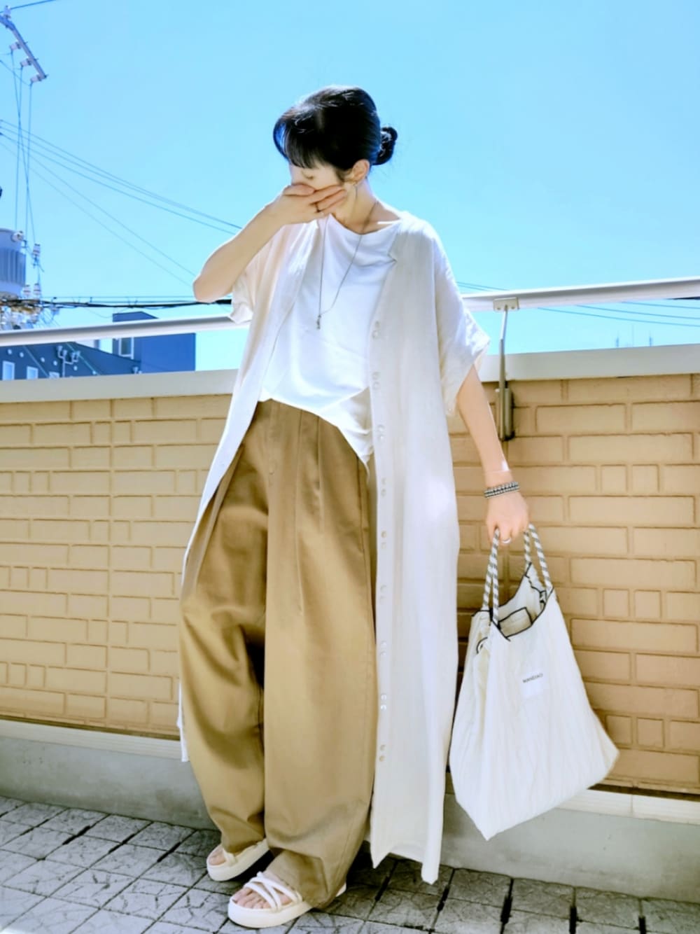 ホワイト系のショルダーバッグ、ベージュ系のチノパンツ、ホワイト系のサンダルを着用したレディースの秋コーディネートの1枚目の写真