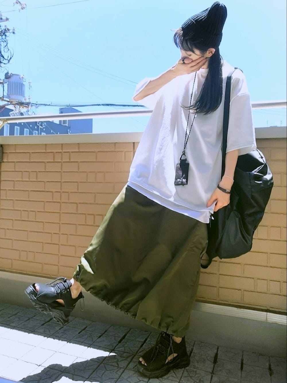 ブラック系のサンダル、グリーン系のスカート、ブラック系のトートバッグを着用したレディースの夏コーディネートの1枚目の写真