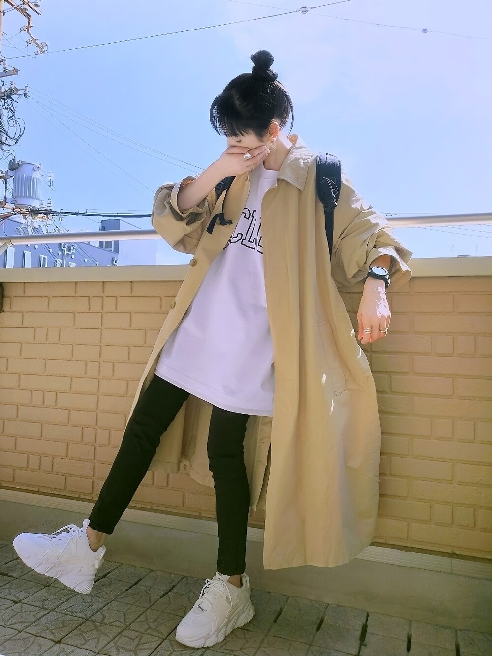 ホワイト系のTシャツ/カットソー、ベージュ系のステンカラーコート、ブラック系のデニムパンツを着用したレディースの春コーディネートの1枚目の写真