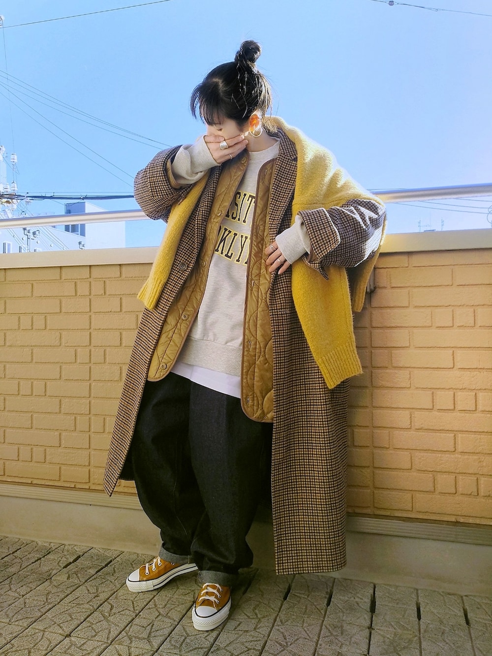 ベージュ系のノーカラージャケット、イエロー系のニット/セーター、ベージュ系のチェスターコートを着用したレディースの冬コーディネートの1枚目の写真
