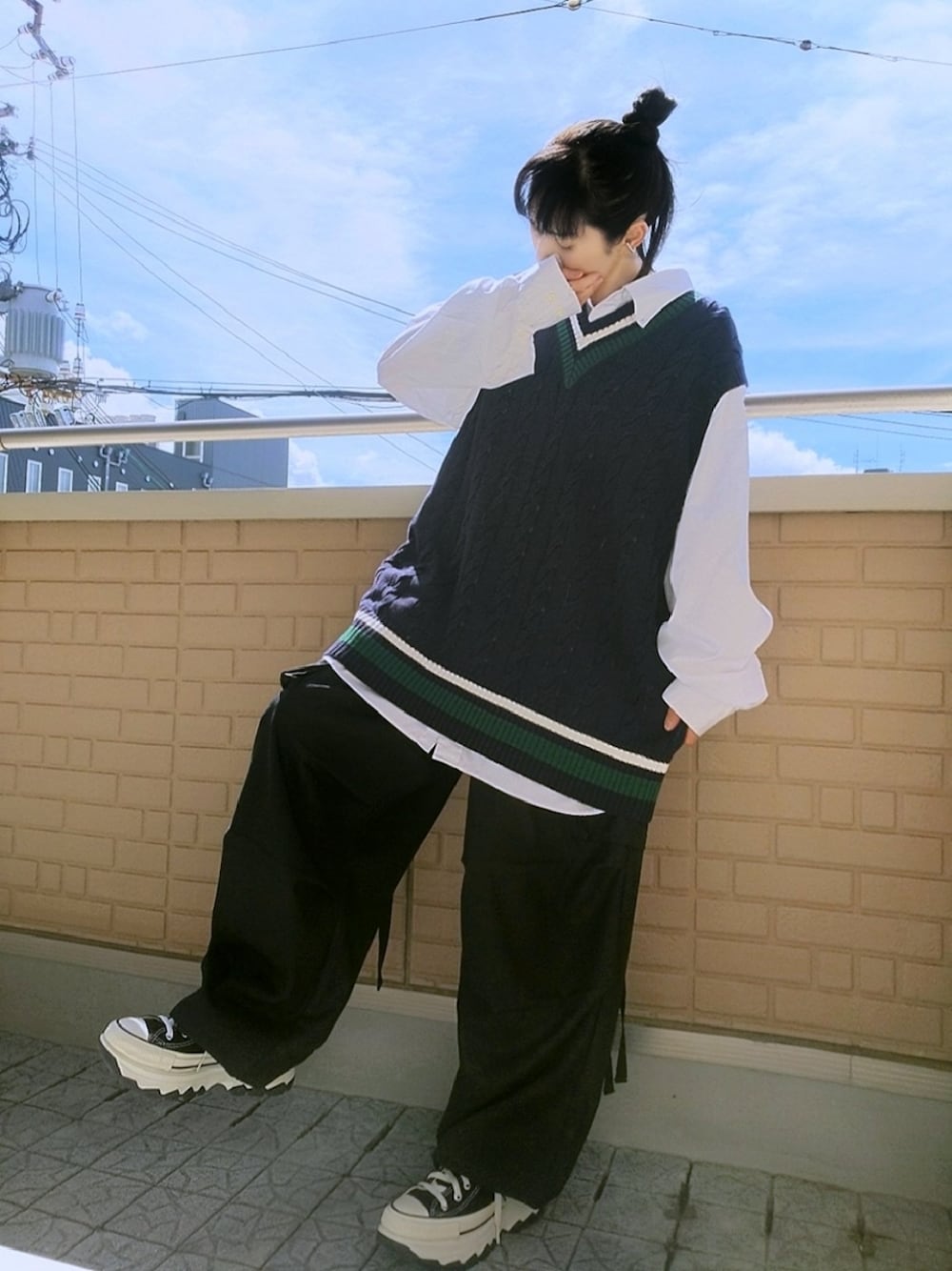 ブラック系のスニーカー、ブラック系のカーゴパンツ、ブルー系のベストを着用したレディースの秋コーディネートの1枚目の写真