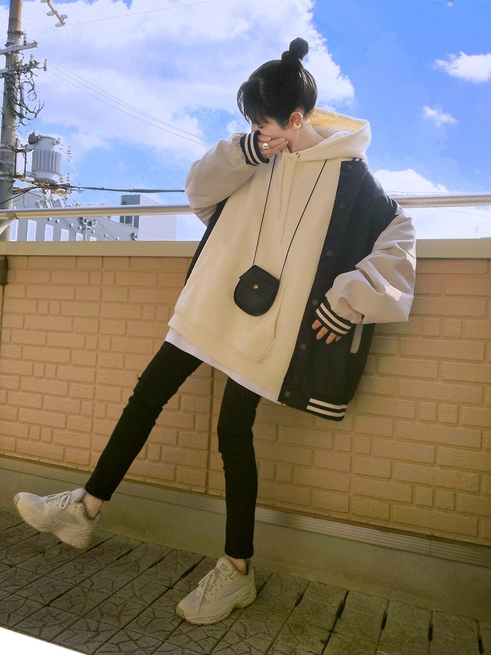 ブラック系のデニムパンツ、ベージュ系のスニーカー、ブラック系のスタジャンを着用したレディースの冬コーディネートの1枚目の写真