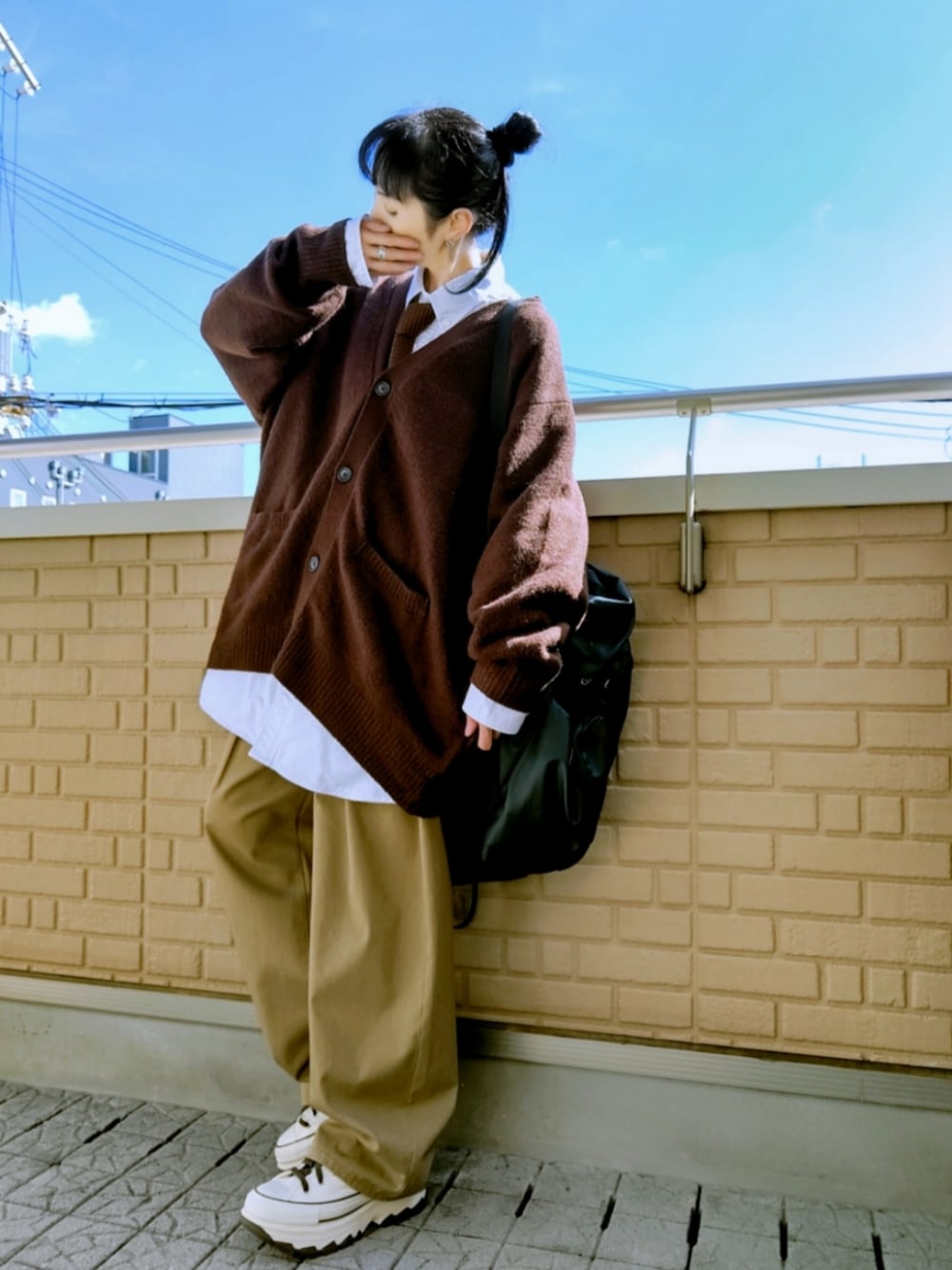 ホワイト系のスニーカー、ベージュ系のチノパンツ、ブラウン系のニット/セーターを着用したレディースの冬コーディネートの1枚目の写真