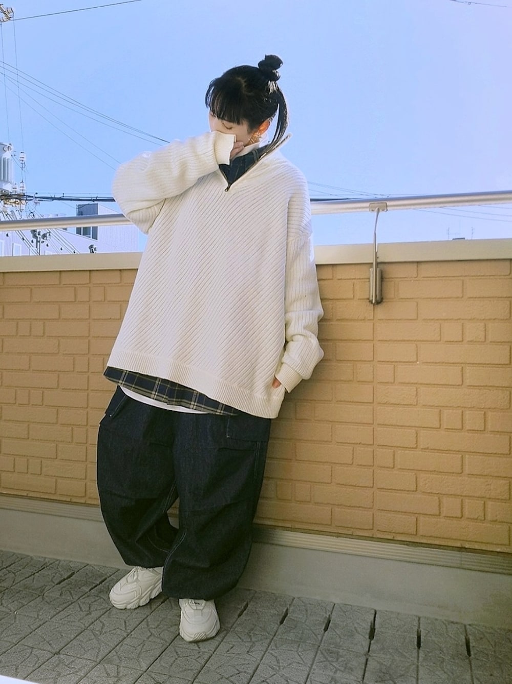 ブルー系のデニムパンツ、ホワイト系のスニーカー、ホワイト系のニット/セーターを着用したレディースの冬コーディネートの1枚目の写真