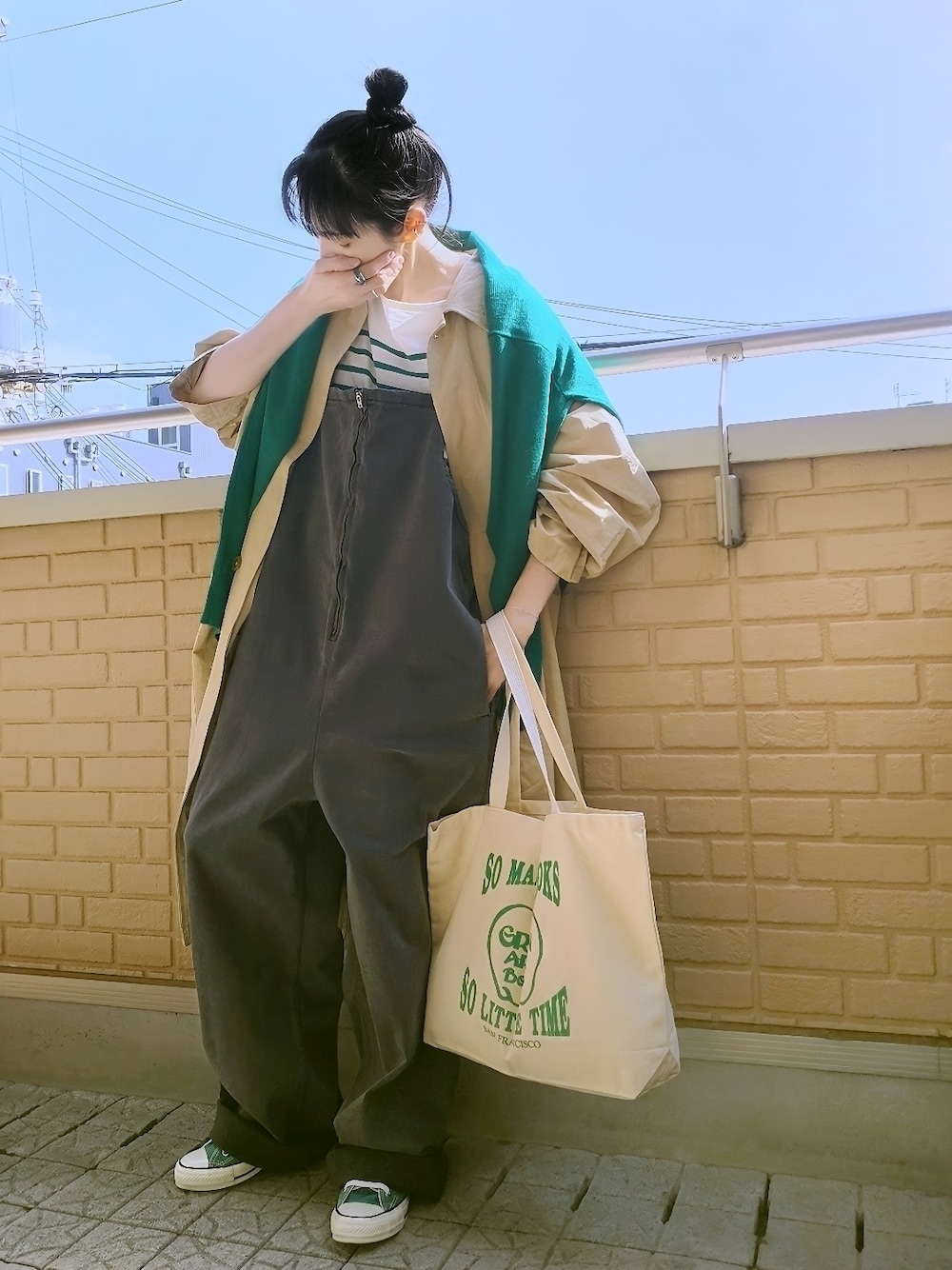 ベージュ系のステンカラーコート、グリーン系のカーディガン/ボレロ、グリーン系のTシャツ/カットソーを着用したレディースの春コーディネートの1枚目の写真