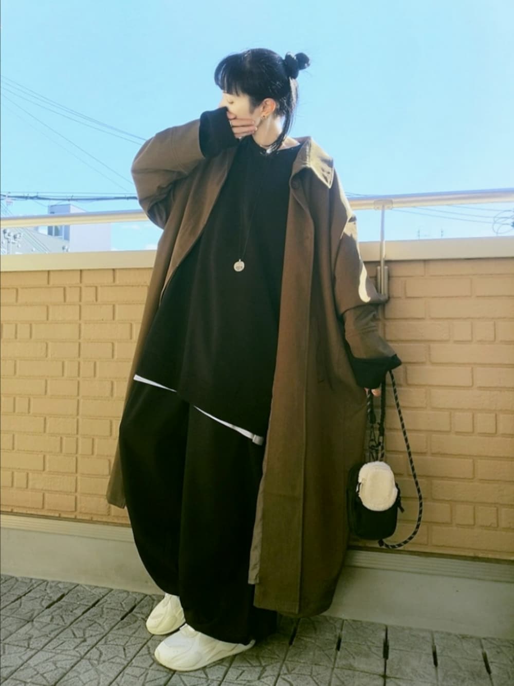 ホワイト系のスニーカー、ブラック系のその他パンツ、ブラウン系のステンカラーコートを着用したレディースの秋コーディネートの1枚目の写真