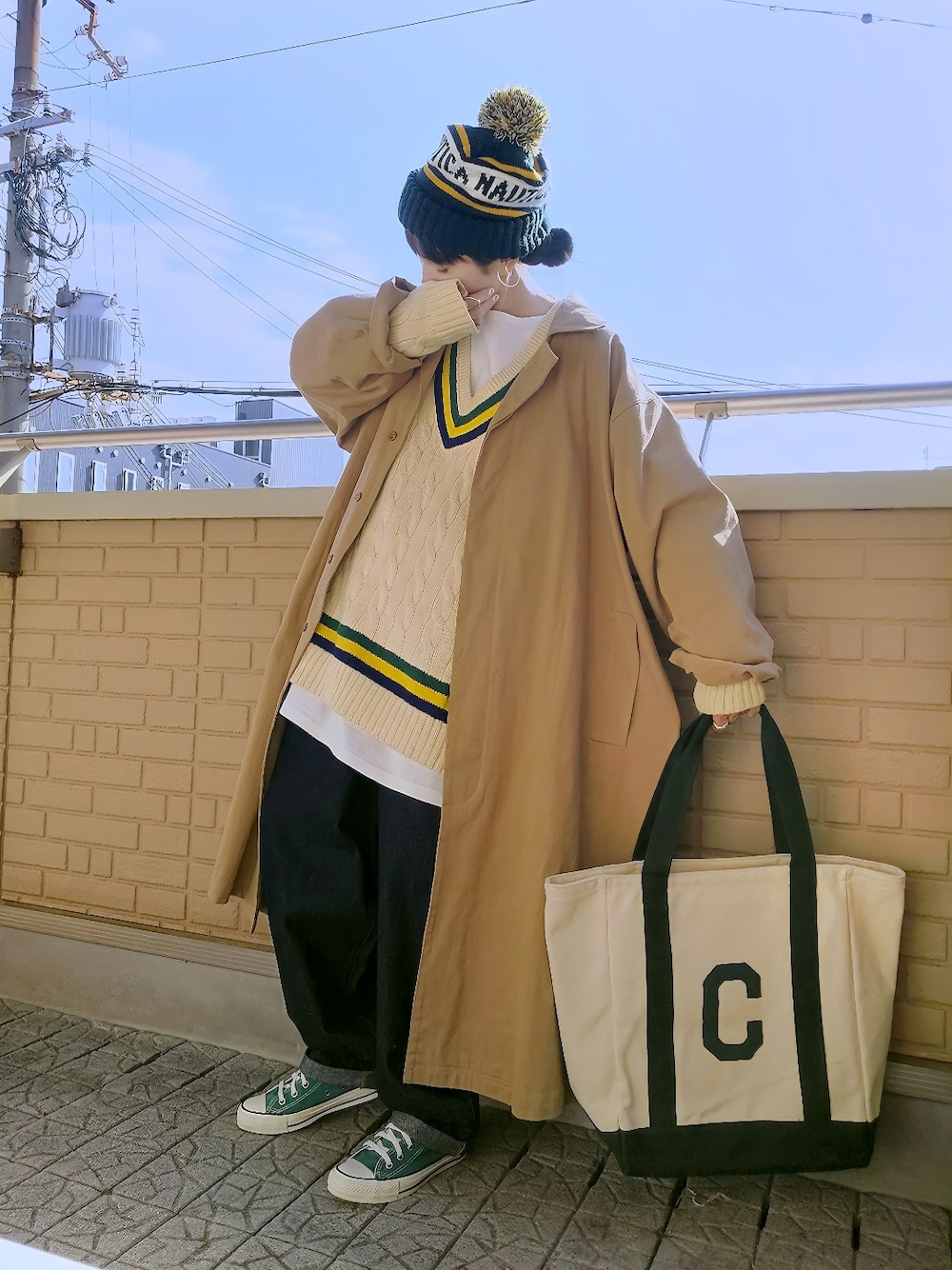 ホワイト系のニット/セーター、ベージュ系のチェスターコート、グリーン系のトートバッグを着用したレディースの冬コーディネートの1枚目の写真