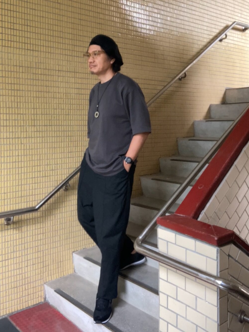 グレー系のTシャツ/カットソー、ブラック系のスラックス、ブラック系のスニーカーを着用したメンズの春コーディネートの1枚目の写真