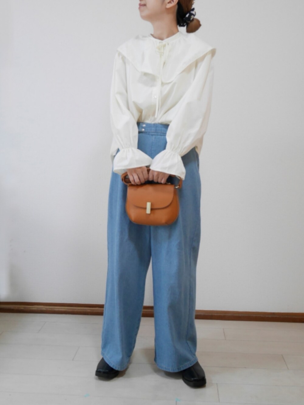 ブルー系のデニムパンツ、ブラウン系のショルダーバッグ、ブラック系のブーツを着用したレディースの春コーディネートの1枚目の写真