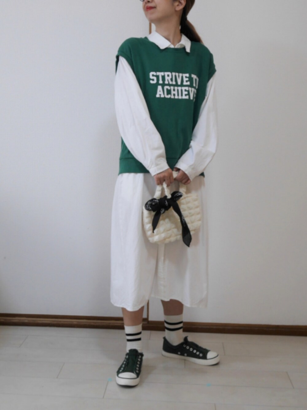 グリーン系のベスト、ホワイト系のトートバッグ、グリーン系のスニーカーを着用したレディースの春コーディネートの1枚目の写真
