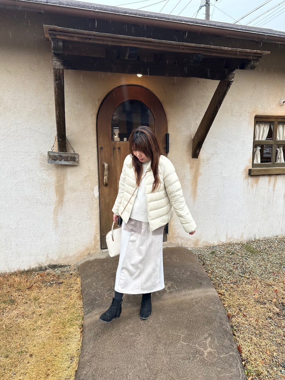 ホワイト系のダウンジャケット/コート、ホワイト系のニット/セーター、ベージュ系のスカートを着用したレディースの冬コーディネートの1枚目の写真