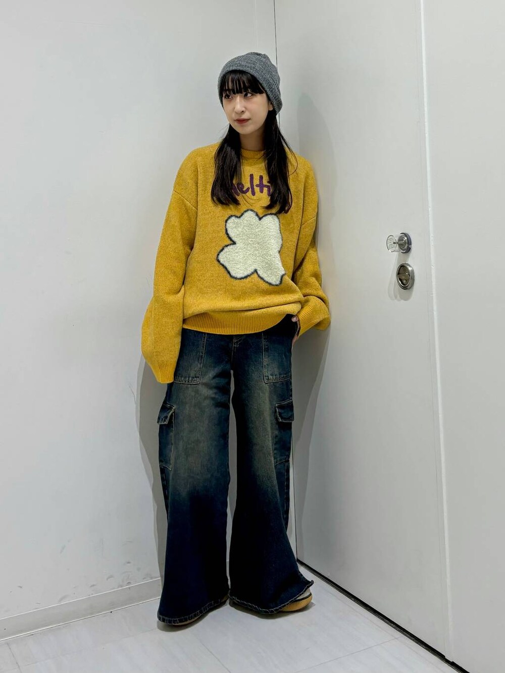 イエロー系のニット/セーター、ブルー系のデニムパンツ、グレー系のニットキャップ/ビーニーを着用したレディースの冬コーディネートの1枚目の写真