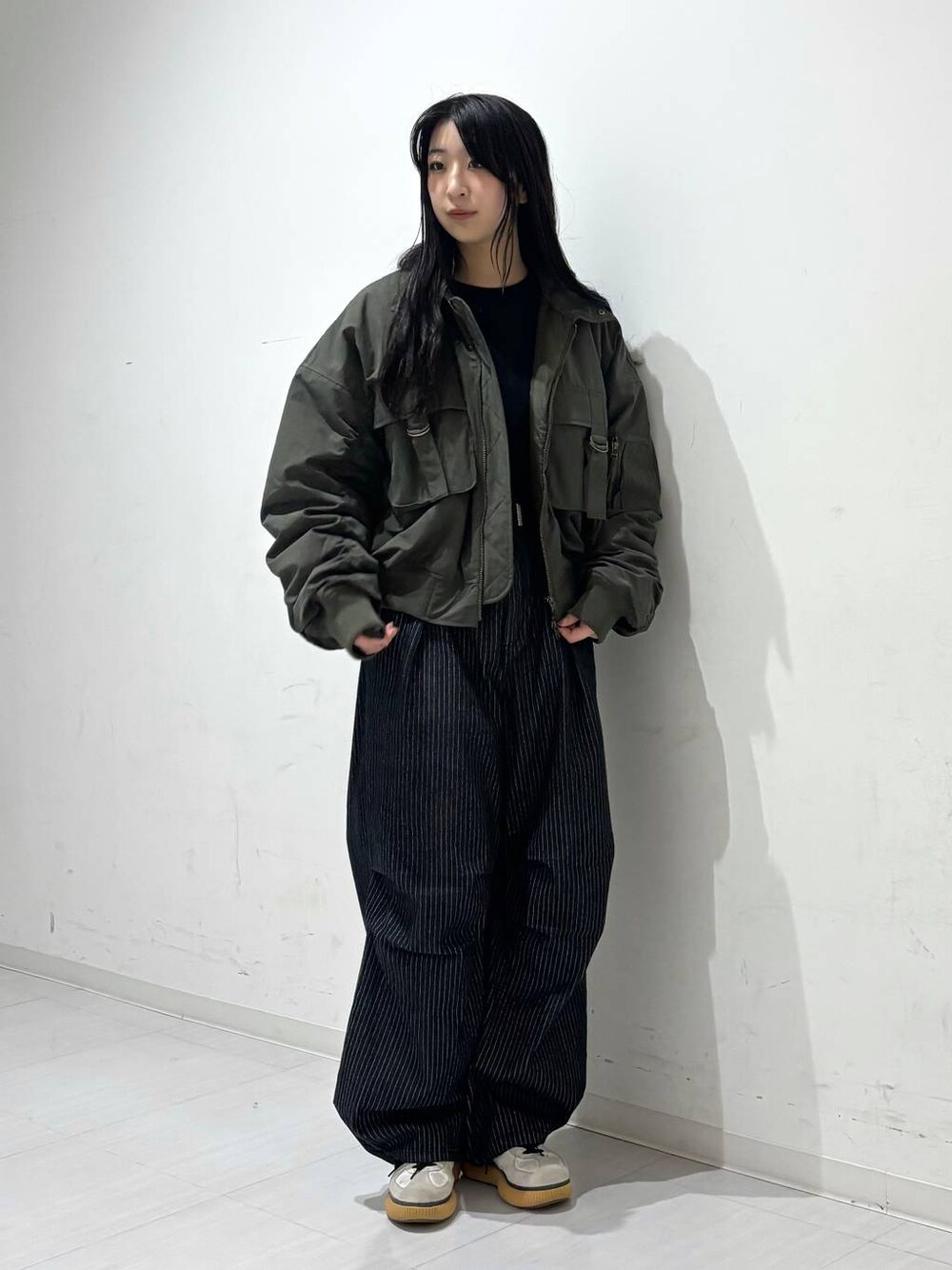 ブラック系のデニムパンツ、グリーン系のブルゾン、ブラック系のスウェットを着用したレディースの秋コーディネートの1枚目の写真