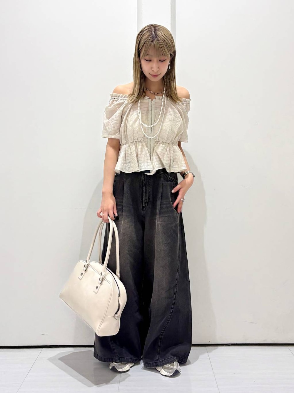 ブラック系のデニムパンツ、ホワイト系のボストンバッグ、ホワイト系のネックレスを着用したレディースの夏コーディネートの1枚目の写真