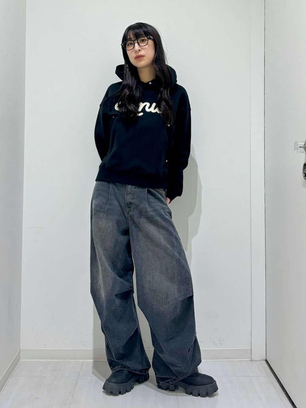 ブラック系のパーカー、ブラック系のブーツ、ブラック系のデニムパンツを着用したレディースの冬コーディネートの1枚目の写真