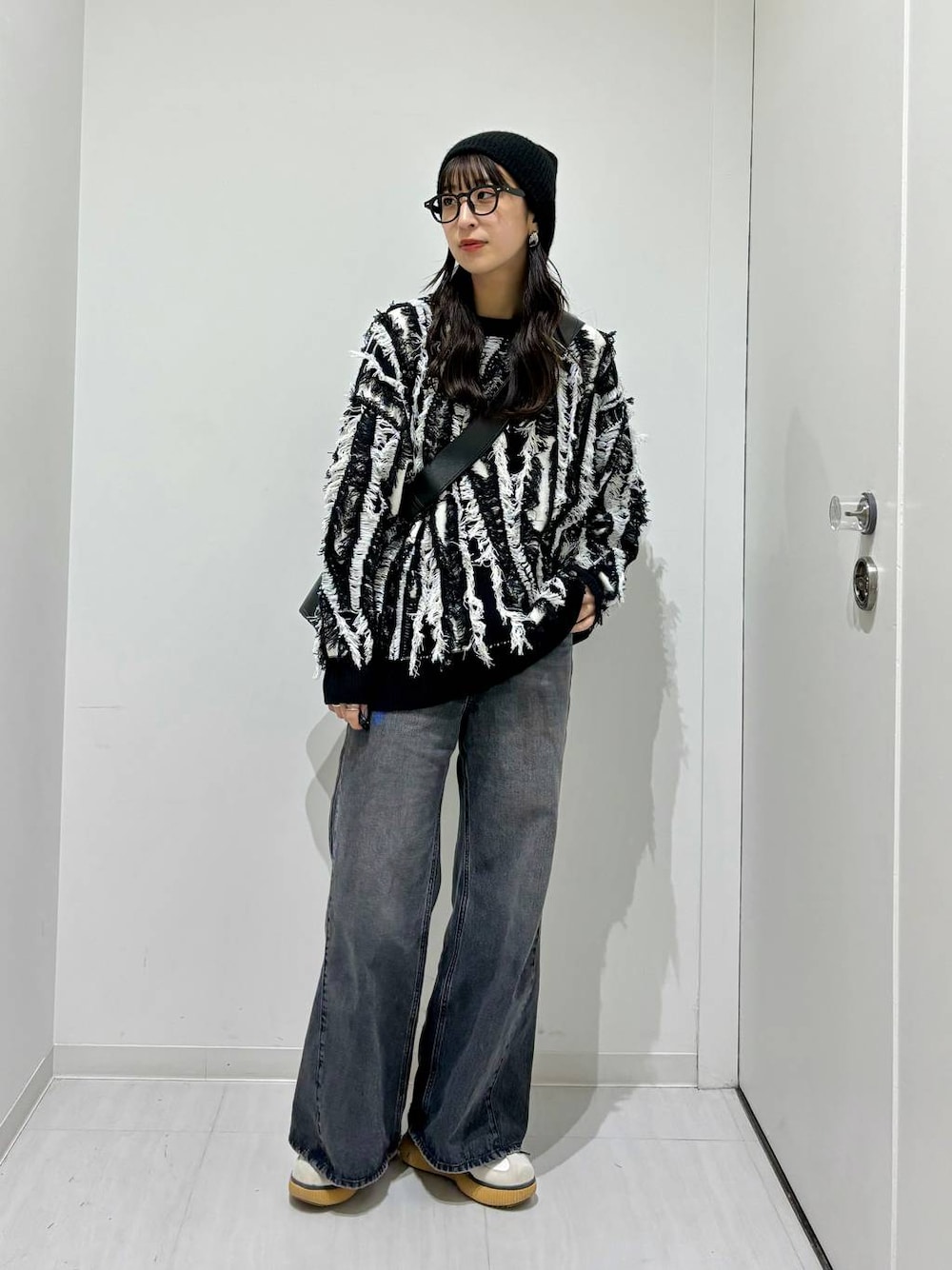 ブラック系のデニムパンツ、ブラック系のニット/セーター、ブラック系のショルダーバッグを着用したレディースの秋コーディネートの1枚目の写真