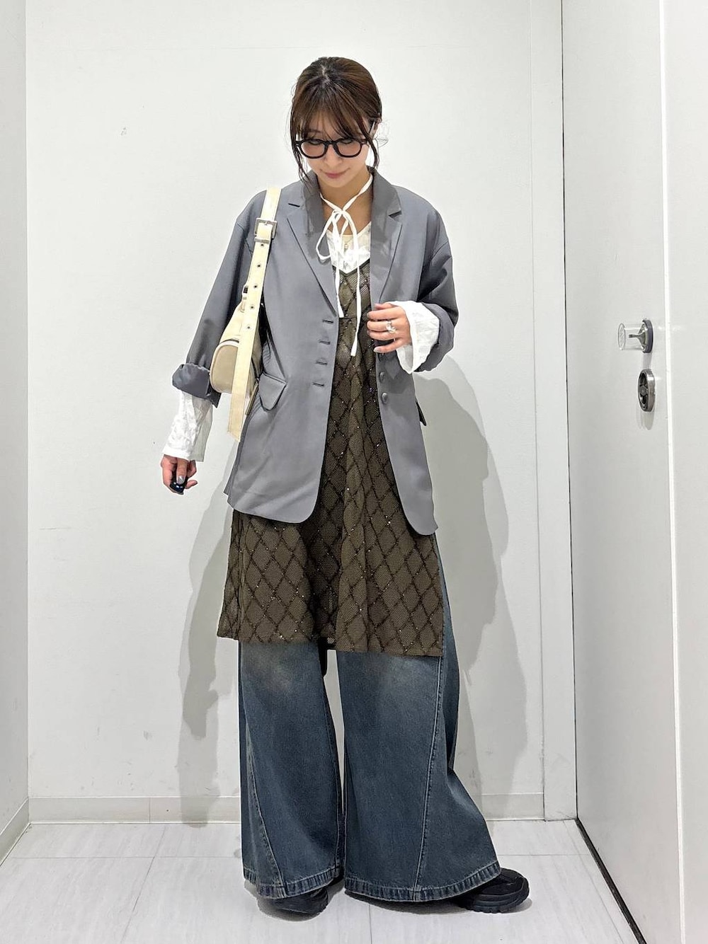 ブルー系のデニムパンツ、ブラック系のスニーカー、ホワイト系のショルダーバッグを着用したレディースの春コーディネートの1枚目の写真