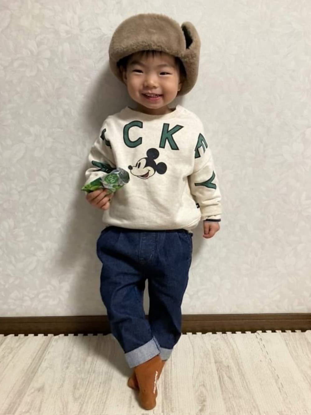 ベージュ系のスウェット、ブルー系のデニムパンツ、グリーン系のキャップを着用したキッズの冬コーディネートの2枚目の写真