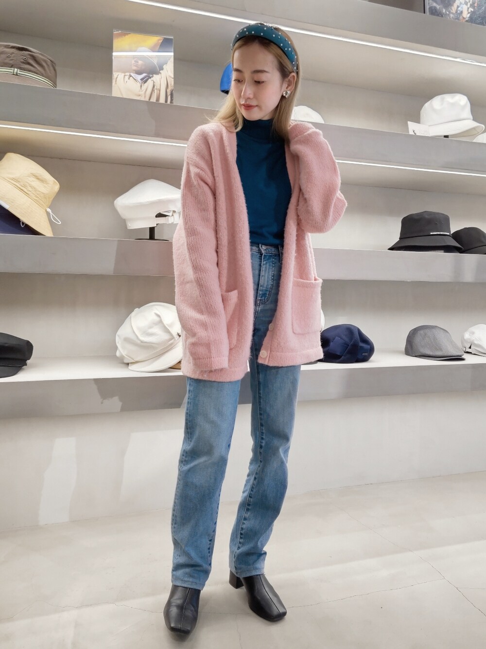 ピンク系のカーディガン/ボレロ、ブルー系のデニムパンツ、グリーン系のヘアバンドを着用したレディースの冬コーディネートの1枚目の写真