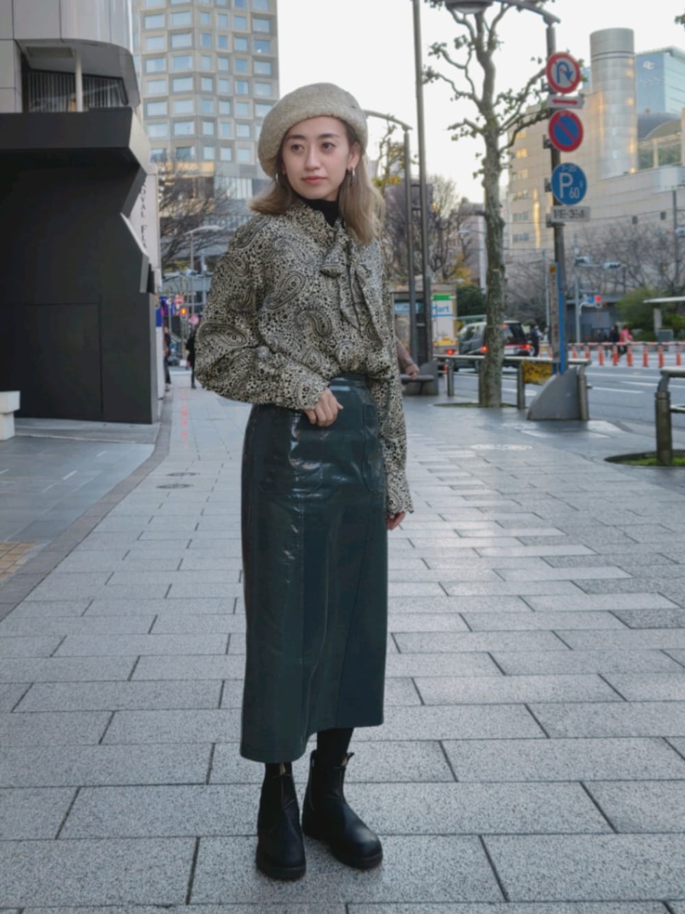 ベージュ系のシャツ/ブラウス、グリーン系のスカート、ブラック系のブーツを着用したレディースの冬コーディネートの1枚目の写真