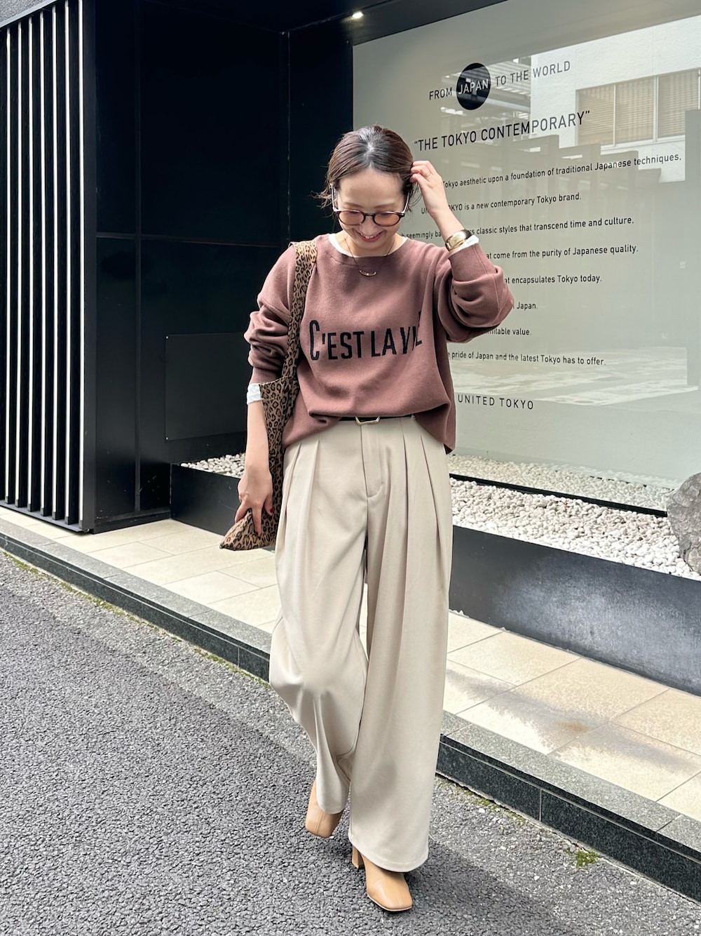 ブラウン系のニット/セーター、ベージュ系のスラックス、その他のトートバッグを着用したレディースの秋コーディネートの1枚目の写真