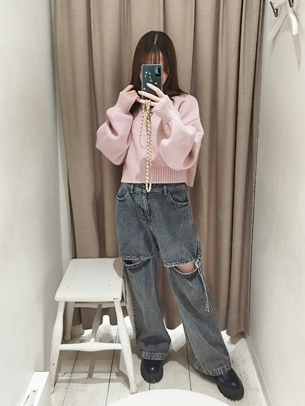 ピンク系のニット/セーター、ブラック系のデニムパンツを着用したレディースの秋コーディネートの1枚目の写真