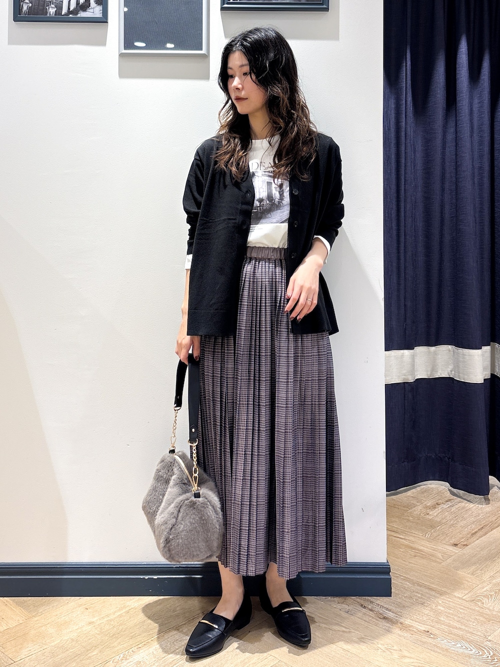 ブラック系のカーディガン/ボレロ、ホワイト系のTシャツ/カットソー、グレー系のスカートを着用したレディースの秋コーディネートの1枚目の写真