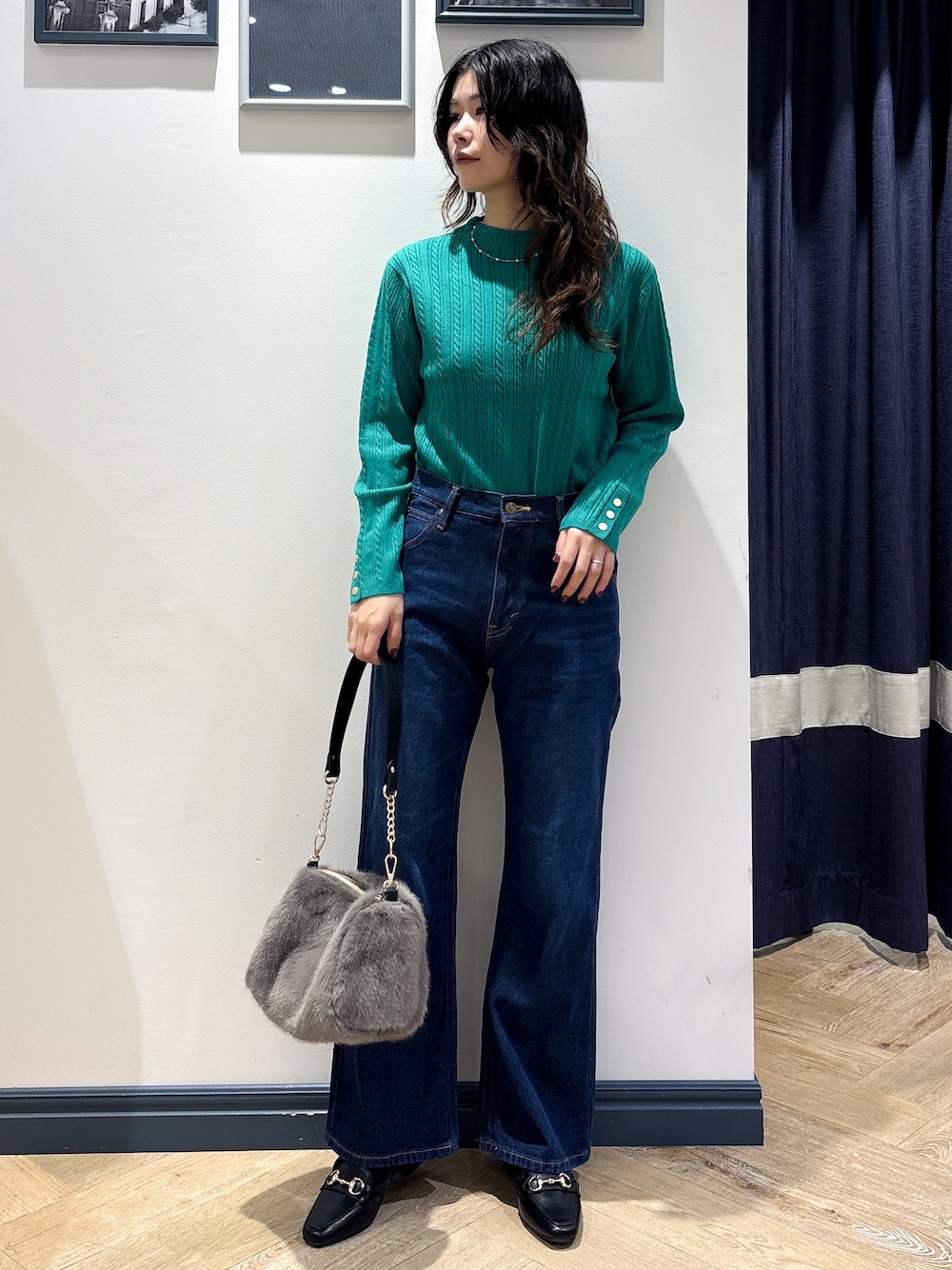 グリーン系のニット/セーター、ブルー系のデニムパンツ、グレー系のショルダーバッグを着用したレディースの秋コーディネートの1枚目の写真