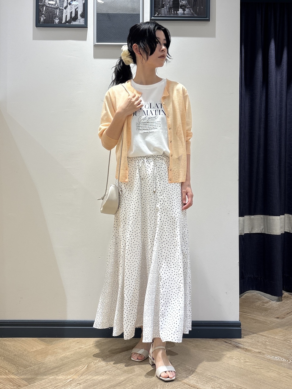 ホワイト系のショルダーバッグ、オレンジ系のカーディガン/ボレロ、ホワイト系のTシャツ/カットソーを着用したレディースの春コーディネートの1枚目の写真
