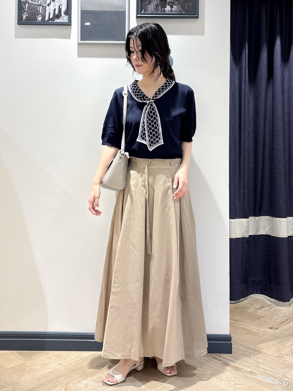 ブルー系のニット/セーター、ベージュ系のスカート、シルバー系のショルダーバッグを着用したレディースの夏コーディネートの1枚目の写真