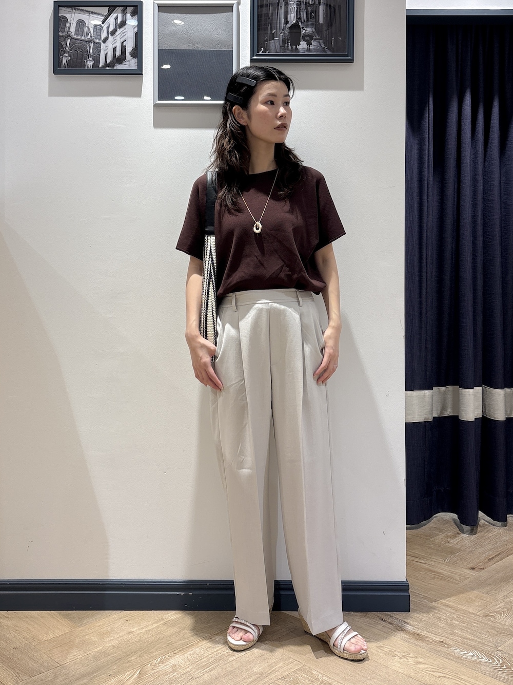 ブラウン系のニット/セーター、ベージュ系のその他パンツ、ブラック系のショルダーバッグを着用したレディースの夏コーディネートの1枚目の写真