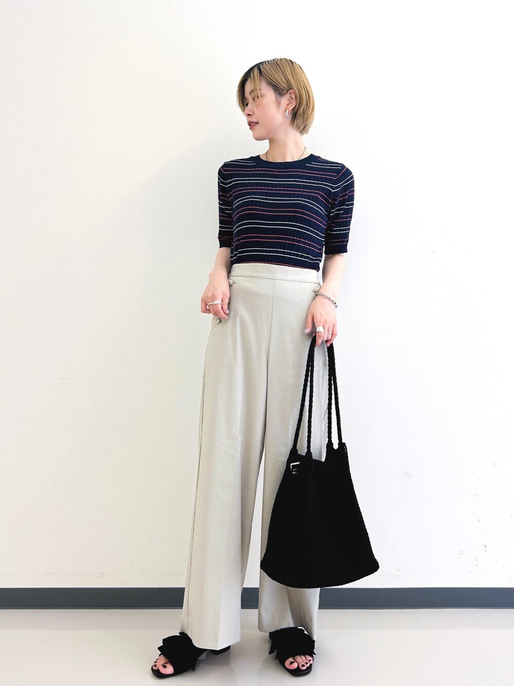 ブルー系のニット/セーター、ブラック系のトートバッグ、ブラック系のサンダルを着用したレディースの春コーディネートの1枚目の写真