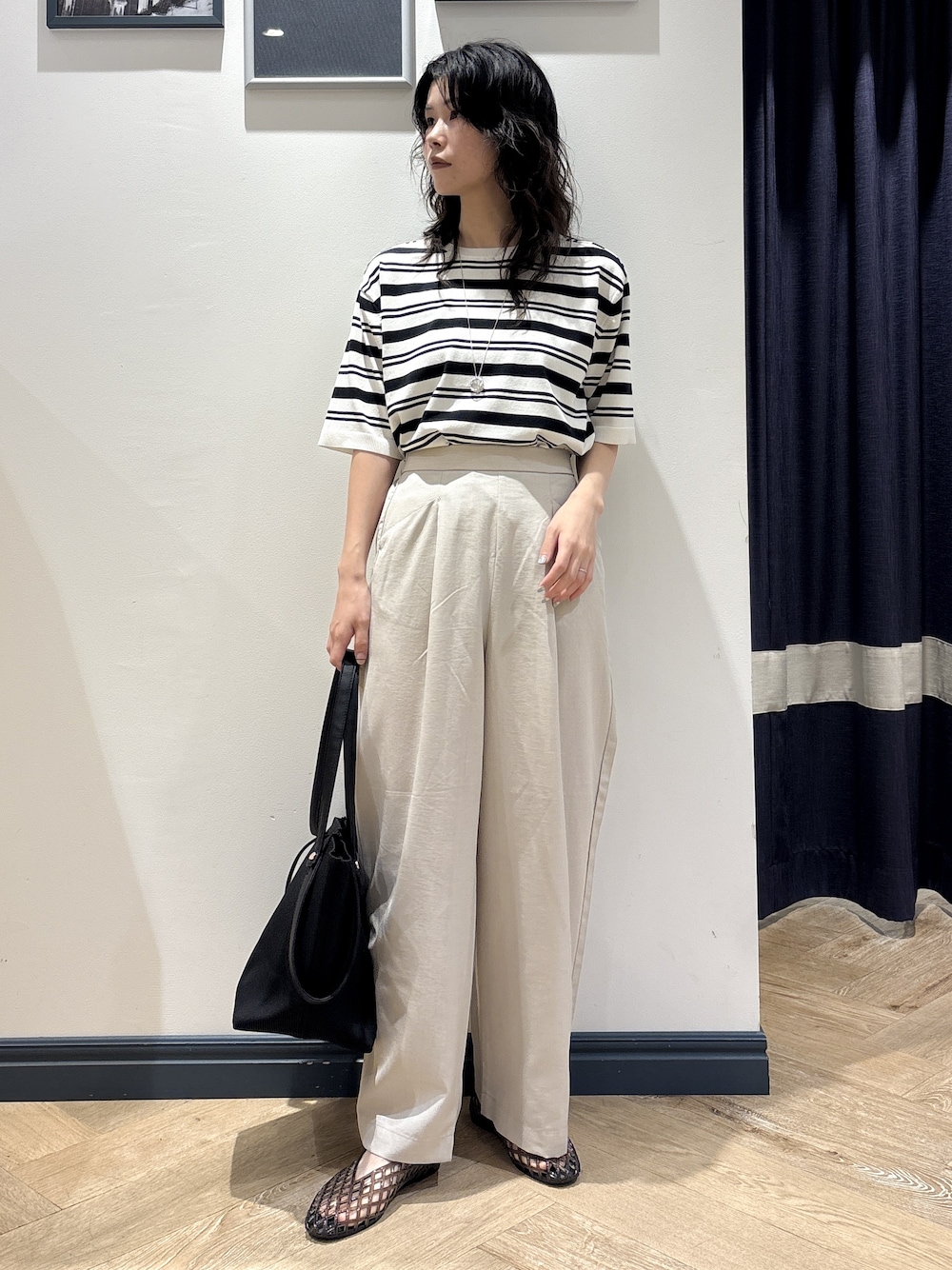 ホワイト系のニット/セーター、ベージュ系のその他パンツ、ブラック系のトートバッグを着用したレディースの夏コーディネートの1枚目の写真
