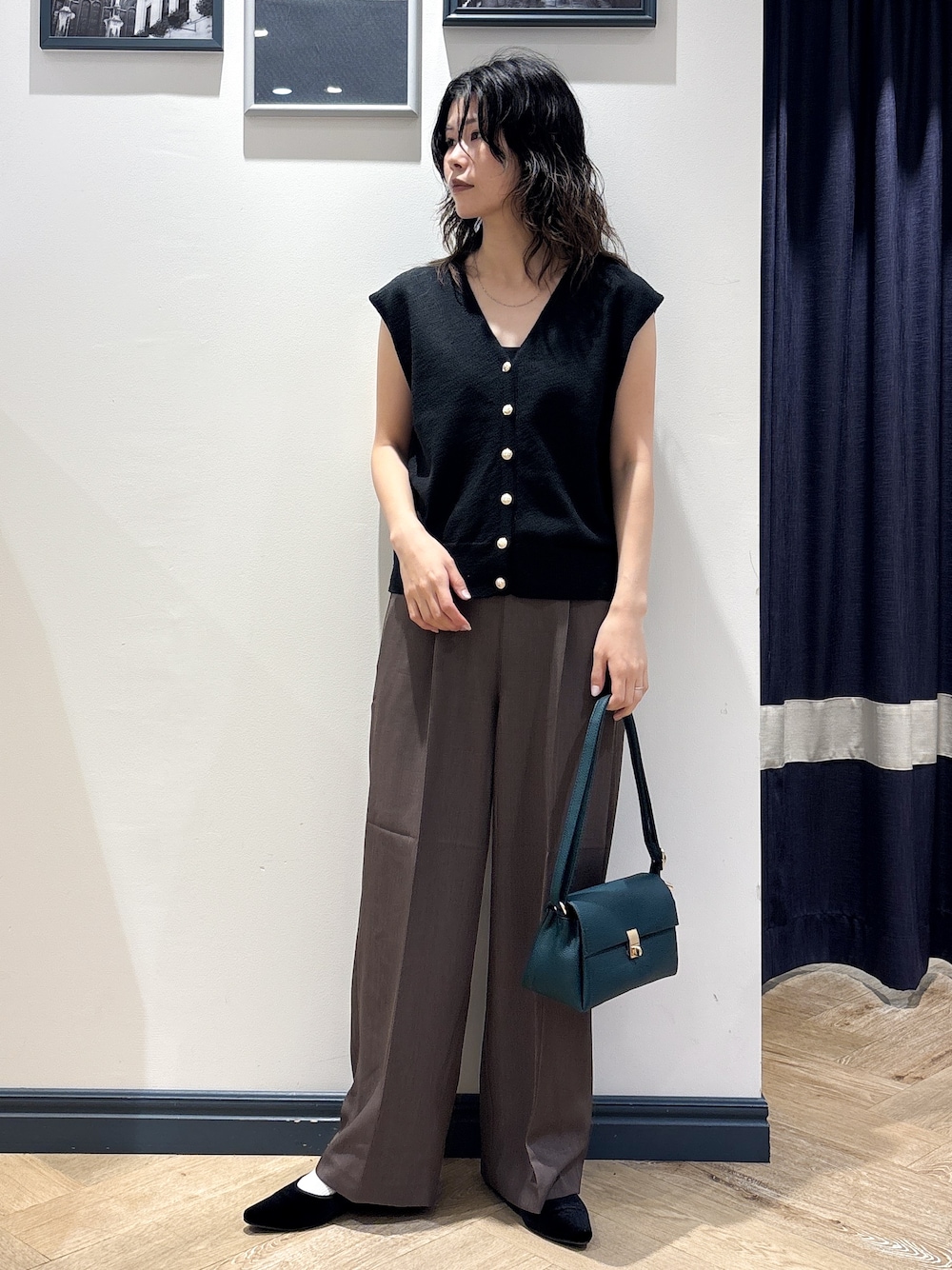ブラック系のニット/セーター、ブラウン系のその他パンツ、グリーン系のショルダーバッグを着用したレディースの夏コーディネートの1枚目の写真